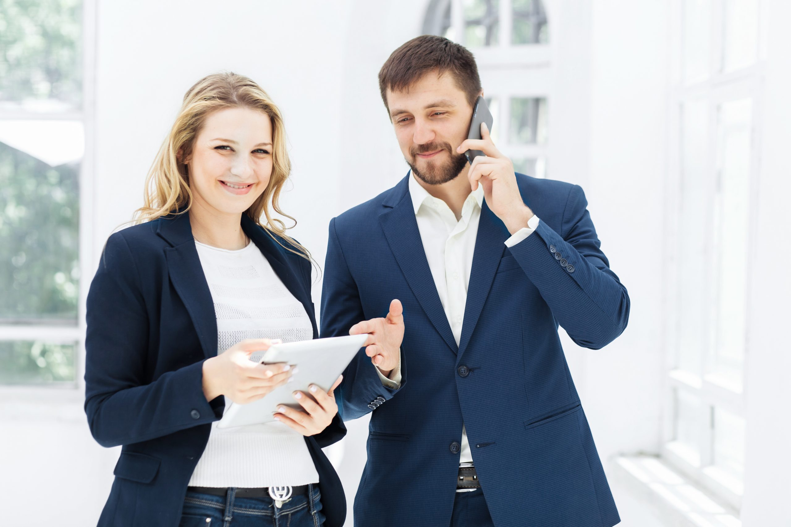 The smiling male and female office workers with laptop and phone